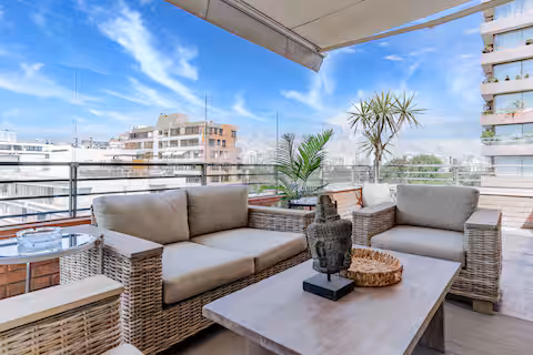 Terraza con sillones de mimbre y vista a la ciudad