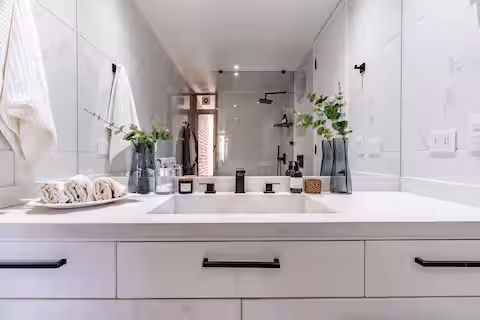 Baño con vanitorio doble y ducha de vidrio