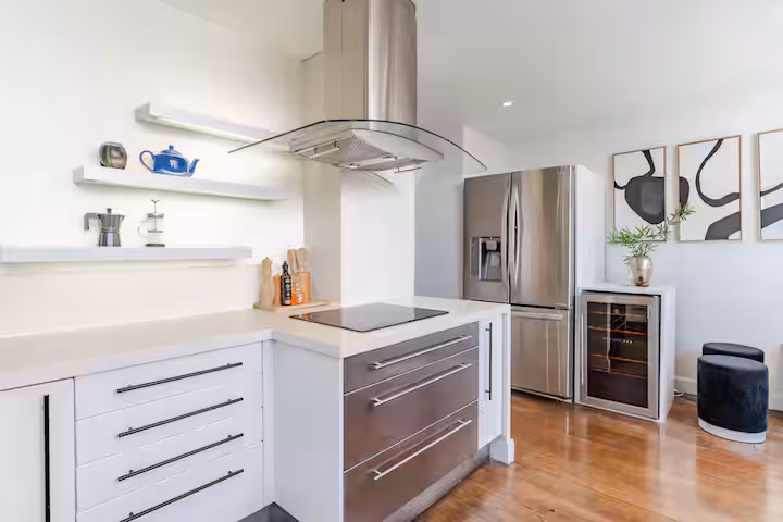 Cocina con refrigerador y muebles blancos