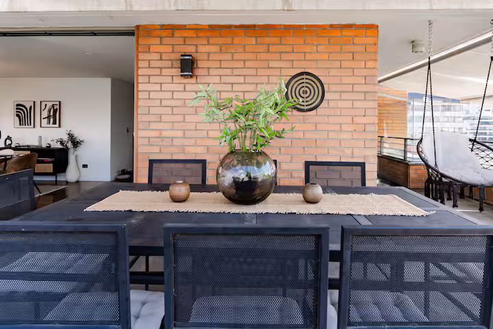 Terraza con mesa de comedor exterior y muro de ladrillo